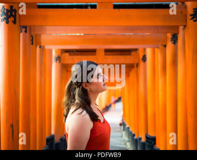 A pretty brunette girl at the vermilion torii gates of Fushimi Inari-Taisha shrine (Fushimi Inari Taisha, Fushimi Inari Shrine) near Kyoto, Japan. Stockfoto
