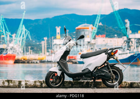 Weiß Sprint Motor Scooter Motorrad Motorrad Fahrrad geparkt gegen Sea Port Dock auf sonnigen Sommertag. Stockfoto