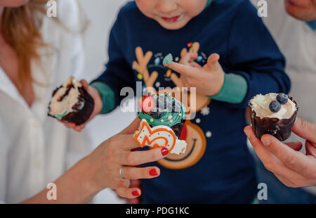 Charmante kleine Junge Ausblasen einer Kerze an seinem Geburtstag Kuchen, wobei im Fokus, und zu versuchen, essen Geburtstagskuchen Stockfoto