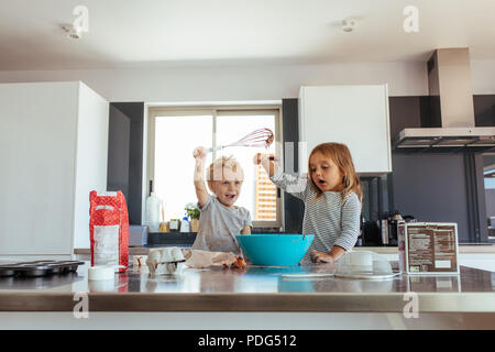 Kleine Jungen und Mädchen mischen Kuchenteig in eine Schüssel geben und in der Küche. Kinder, die Spaß bei der Kuchen in der Küche. Stockfoto