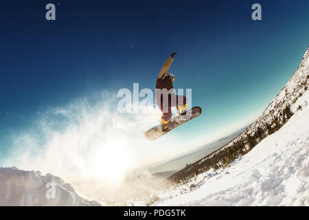Snowboarder springt für die lange Distanz von Sprungbrett Stockfoto