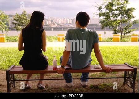 Asiatische Paar sitzt auf der Bank durch den Fluss Han, Hangang. In Gespräch und dating in Seoul, Südkorea. Stockfoto