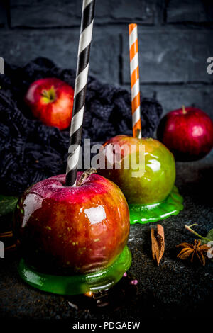 Traditionelle herbst Delikatesse, Äpfel in Karamell Glasur. Auf einem dunklen Hintergrund, mit Äpfeln, Blätter, Karamellsauce und eine warme Decke. Kopieren Sie Platz für Text Stockfoto