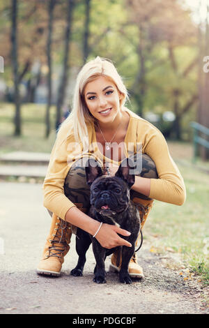 Schöne und glückliche Frau genießen im Herbst park mit ihren liebenswerten Französische Bulldogge. Stockfoto