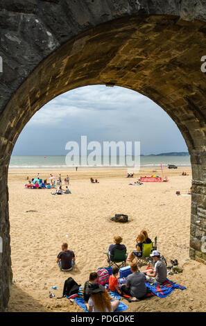 Familie Unterschlupf unter einem alten Steinbogen am Strand in Swansea, Wales Stockfoto