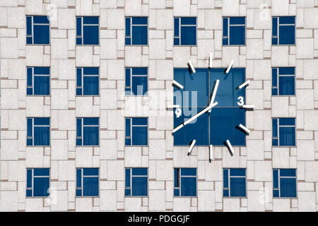 Uhr auf ein zeitgenössisches Gebäude Fassade mit mehreren identischen Windows Stockfoto