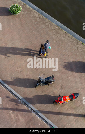 Luftbild vom Fenster des Hiltn Doubletree von zwei Fußgänger und zwei Motorräder auf dem Bürgersteig, oosterdok, Amsterdam, Niederlande, Europa Stockfoto