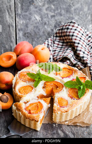 Hausgemachter Käsekuchen mit Aprikosen auf hölzernen Tisch Stockfoto