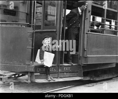 Fünf Jahre alten Newsie springt auf und weg von Straßenbahnen, um Zeitungen zu verkaufen 1910 Stockfoto