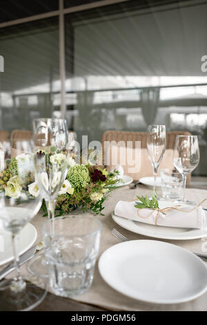 Hochzeit oder Gala Dinner. Die Tische und Stühle für Gäste, serviert mit Besteck und Geschirr. Mit einem Leinen Tischdecke Läufer abgedeckt. Party auf der Terrasse Stockfoto