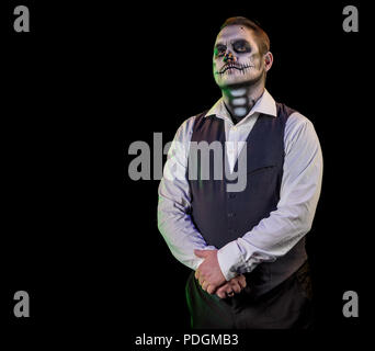 Porträt von einem gut gekleideten Mann mit Totenkopf Make-up. Horror und Halloween Motto, mit Bühnenbeleuchtung und Effekte Schuß Stockfoto