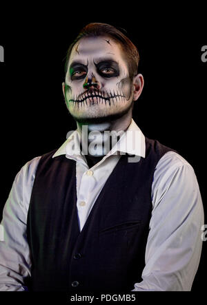 Porträt von einem gut gekleideten Mann mit Totenkopf Make-up. Horror und Halloween Motto, mit Bühnenbeleuchtung und Effekte Schuß Stockfoto