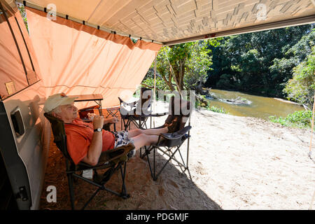 Reife männliche Wohnmobil entspannen unter einer Markise Campingplatz am Barron River, Biboohra, Far North Queensland, FNQ, QLD, Australien Stockfoto