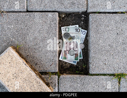 Polnischer Zloty Banknoten und Münzen im Rahmen einer losen Pflaster Ziegel gefunden. Konzept des Laufens aus persönlichen Ersparnissen Stockfoto