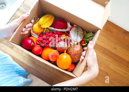 Junge Frau mit einer Kiste mit Obst und Gemüse in der Küche zu Hause. Close Up. Ansicht von oben. Gesundes Leben Konzept Stockfoto