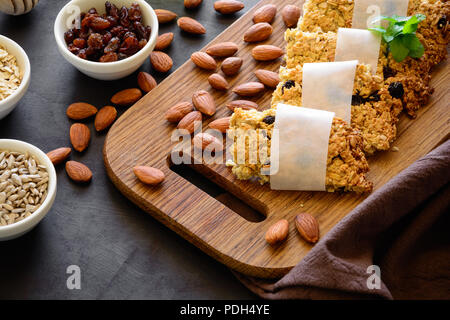 Superfoods Frühstück bars mit Hafer, Sesam, Sonnenblumenkerne, Honig und Nüssen auf braunem Holz- Hintergrund. Gesunde Ernährung Konzept Stockfoto