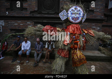 Bhaktapur, Nepal. 9 Aug, 2018. Anhänger sitzen in der Nähe von Stroh Bildnis des mythischen Daemon Ghanta Karna vor dem Brennen während der Feierlichkeiten der Hindu festival Gathemangal in Bhaktapur, Nepal am Donnerstag, August 09, 2018. Nach Mythen Es wird angenommen, dass durch die Verbrennung der Dämon befreien, böse Geister und Krankheiten von Kindern. Credit: Skanda Gautam/ZUMA Draht/Alamy leben Nachrichten Stockfoto