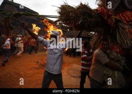 Bhaktapur, Nepal. 9 Aug, 2018. Anhänger tragen ein Stroh Bildnis des mythischen Daemon Ghanta Karna bei Feiern der Hindu festival Gathemangal in Bhaktapur, Nepal am Donnerstag, August 09, 2018 zu brennen. Nach Mythen Es wird angenommen, dass durch die Verbrennung der Dämon befreien, böse Geister und Krankheiten von Kindern. Credit: Skanda Gautam/ZUMA Draht/Alamy leben Nachrichten Stockfoto