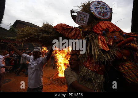 Bhaktapur, Nepal. 9 Aug, 2018. Anhänger tragen ein Stroh Bildnis des mythischen Daemon Ghanta Karna bei Feiern der Hindu festival Gathemangal in Bhaktapur, Nepal am Donnerstag, August 09, 2018 zu brennen. Nach Mythen Es wird angenommen, dass durch die Verbrennung der Dämon befreien, böse Geister und Krankheiten von Kindern. Credit: Skanda Gautam/ZUMA Draht/Alamy leben Nachrichten Stockfoto