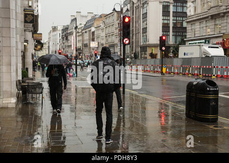 London, Großbritannien. 9. August 2018. Die typisch englischen Sommer kehrt in den Strang in Central London. Die rekordverdächtigen Hitzewelle gab den Weg zu mehr Typisch englisches Wetter wie Regen auf den Strang in Central London gegossen. Sonnenschirme und leichte Sommer Schuhe gemacht unpassend Partnerschaften als Busse, Autos, Taxis, Radfahrer und Fußgänger alle braved den Regenguß, wie sie über ihr Geschäft ging. © Peter Hogan/Alamy leben Nachrichten Stockfoto