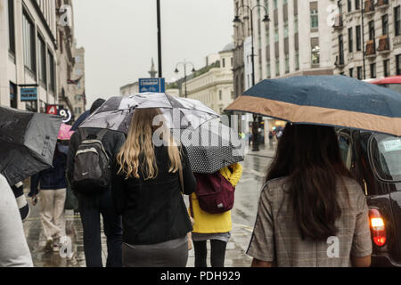 London, Großbritannien. 9. August 2018. Die typisch englischen Sommer kehrt in den Strang in Central London. Die rekordverdächtigen Hitzewelle gab den Weg zu mehr Typisch englisches Wetter wie Regen auf den Strang in Central London gegossen. Sonnenschirme und leichte Sommer Schuhe gemacht unpassend Partnerschaften als Busse, Autos, Taxis, Radfahrer und Fußgänger alle braved den Regenguß, wie sie über ihr Geschäft ging. © Peter Hogan/Alamy leben Nachrichten Stockfoto