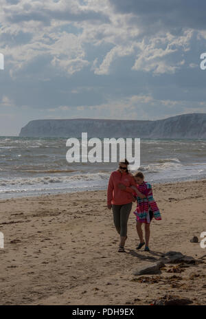 Compton Bay auf der Isle of Wight, Großbritannien. 9. August 2018. Nach einer Hitzewelle, Kühler verunsichert seeminglyendless consition mehr im Einklang mit dem jahreszeitlichen Durchschnitt Temperaturen zum Strand von Compton Bay auf der Isle of Wight zurück. Familien und Freund zu Fuß am Strand und nutzen Sie die kühleren Temperaturen im Sommer und ungeklärten Bedingungen mit einer steifen Brise. Quelle: Steve Hawkins Fotografie/Alamy leben Nachrichten Stockfoto