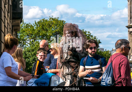 Edinburgh, Schottland, Großbritannien. 9. August 2018. Edinburgh Fringe Festival, Royal Mile, Edinburgh, Schottland, Vereinigtes Königreich. An einem sonnigen Festival Tag der Jungfrau Geld gesponsert Street Festival mit Menschen und fringe Darsteller verpackt ist. Eine weibliche Street Performer gekleidet wie eine geisterhafte Frau steht über der Fußgänger Stockfoto