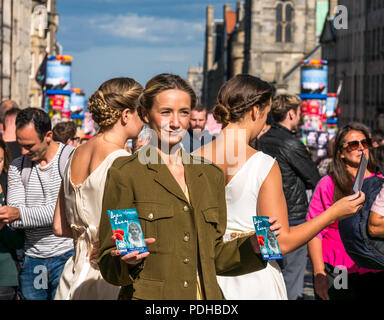 Edinburgh, Schottland, Großbritannien. 9. August 2018. Edinburgh Fringe Festival, Royal Mile, Edinburgh, Schottland, Vereinigtes Königreich. An einem sonnigen Festival Tag der Jungfrau Geld gesponsert Street Festival mit Menschen und fringe Darsteller verpackt ist. Eine Gruppe von hübschen jungen Frauen im Zweiten Weltkrieg Kostüme gekleidet hand Flyer für Ihre Fringe Show namens Liebe Lucy Stockfoto