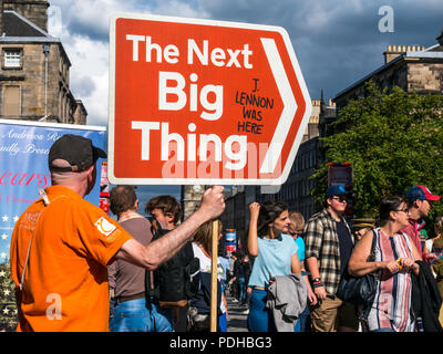 Edinburgh, Schottland, Großbritannien. 9. August 2018. Edinburgh Fringe Festival, Royal Mile, Edinburgh, Schottland, Vereinigtes Königreich. An einem sonnigen Festival Tag der Jungfrau Geld gesponsert Street Festival mit Menschen und fringe Darsteller verpackt ist. Ein Mann mit einem Pfeil Schild, das nächste große Ding Stockfoto