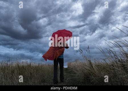 Ein Mann verliert seinen Regenschirm an einem stürmischen Tag in England. Großbritannien Stockfoto