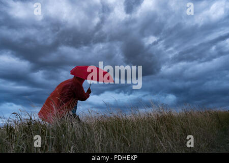 Ein Mann verliert seinen Regenschirm an einem stürmischen Tag in England. Großbritannien Stockfoto