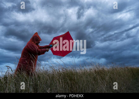 Ein Mann verliert seinen Regenschirm an einem stürmischen Tag in England. Großbritannien Stockfoto