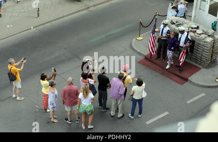 Berlin, Deutschland. 09 Aug, 2018. Am Checkpoint Charlie, dem früheren Grenzübergang zwischen West- und Ost-Berlin, Touristen sind mit Schauspielern, die in Uniformen der US-Soldaten vor einer rekonstruierten historischen Allied Border House fotografiert. Quelle: Wolfgang Kumm/dpa/Alamy leben Nachrichten Stockfoto