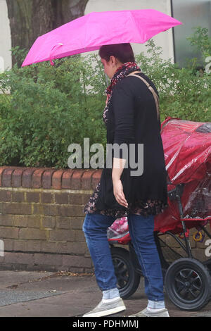 London. UK 10 Aug 2018 - eine Frau, die Schutz unter einer rosa Regenschirm wie Es beginnt in zwischen sonnigen Perioden in London zu regen. Nach dem Met Office die ungeklärte Wetter ist wahrscheinlich in den nächsten Tagen fortzusetzen. Credit: Dinendra Haria/Alamy leben Nachrichten Stockfoto