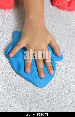Ein Kind, das eine Hand drucken in einigen Weiche biegsame blau Modelliermasse Stockfoto