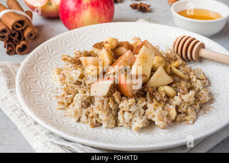 Haferbrei mit frischen Äpfeln, Nüssen und Zimt für das Frühstück auf dem Tisch, Nahaufnahme, horizontal. Stockfoto