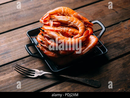 Köstliche Garnelen in einer Pfanne auf einem Holztisch Stockfoto