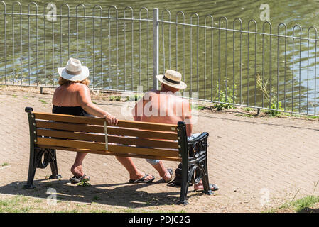 Ältere Urlauber auf einer Bank Sonnen in Trenance Park in Newquay Cornwall sitzen. Stockfoto