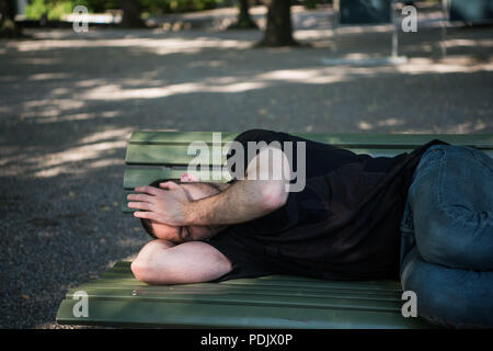 Armen Obdachlosen schlafen auf der Holzbank im Park Stockfoto