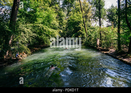 München, Deutschland - 29. Juli 2018: Die Schwimmer auf den sich schnell bewegenden Eisbach, ein kleiner Mann -, die 2 km lange schnelle Stromschnellen im Englischen Garten, München Stockfoto