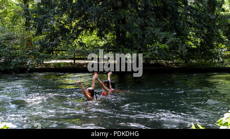 München, Deutschland - 29. Juli 2018: Die Schwimmer auf den sich schnell bewegenden Eisbach, ein kleiner Mann -, die 2 km lange schnelle Stromschnellen im Englischen Garten, München Stockfoto