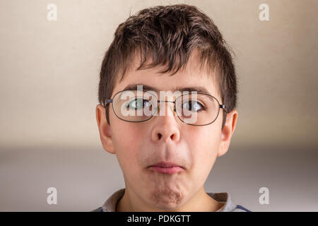 Boy saugt Wangen und drückt seine Lippen, die sonderbaren Gesicht als Zeichen der Überraschung Stockfoto