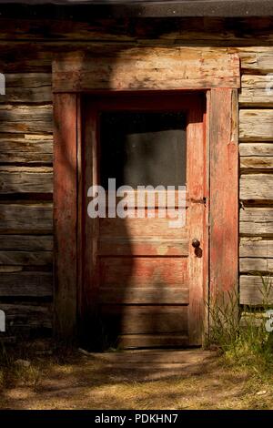 Kabinentür und Abstellgleis: Sonnenlicht und Schatten necken die verwitterte Tür in dieser frühen Morgen Foto in einem Montana Geisterstadt genommen. Stockfoto