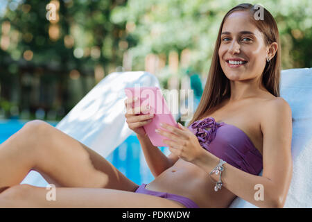 Strahlende Frau liegen in der Nähe von Pool genießen Sie die umliegende Natur Stockfoto