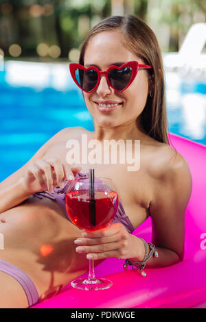 Stilvolle Frau Helle rote Sonnenbrille liegen auf Luftmatratze Stockfoto