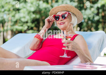 Reife Frau Gefühl glücklich, während der Rest in der Nähe von Pool Stockfoto