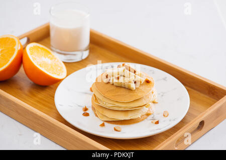 Stapel von leckeren Pfannkuchen mit Schokolade, Honig, Nüsse und Bananenscheiben auf Platte auf Stein Hintergrund Stockfoto