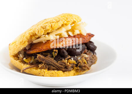 Arepas gefüllt mit geschredderten Rindfleisch, schwarze Bohnen, Kochbananen und Käse serviert in einem weißen Teller auf weißem Hintergrund Stockfoto