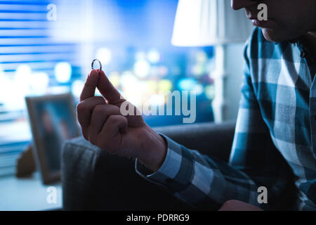 Scheidung, Beziehungsprobleme, als Single oder bedauern Konzept. Schwere Mann traurig bei der Hochzeit oder Verlobungsring Home Suchen spät in der Nacht. Stockfoto