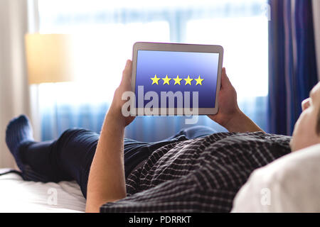 Überprüfung und fünf Sterne mit mobile Anwendung. Umfrage zur Kundenzufriedenheit und Feedback app auf Tablet. Mann mit modernen intelligenten Gerät zuhause. Stockfoto